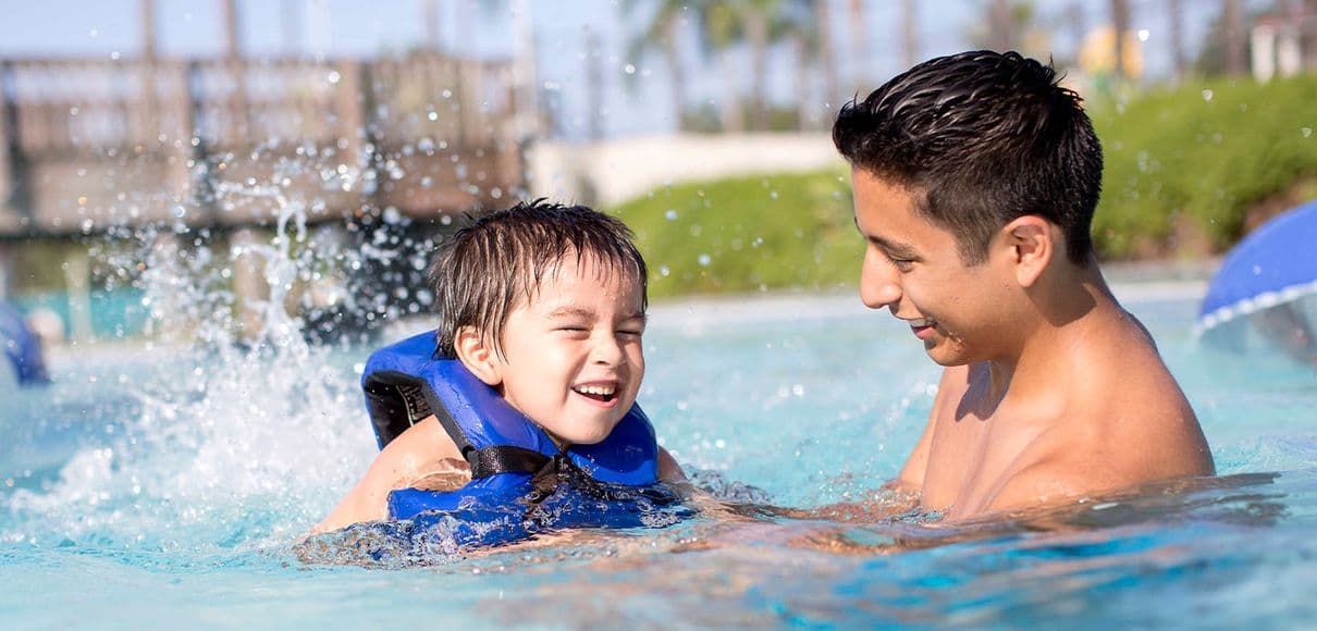Parents and children in a kids' activity pool at a waterpark.